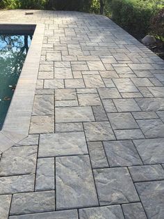 a stone patio next to a swimming pool