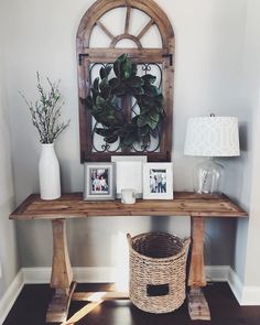 a wooden table topped with pictures and a basket next to a wall mounted planter