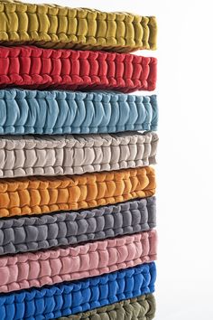 a stack of folded towels sitting on top of each other in different colors and patterns