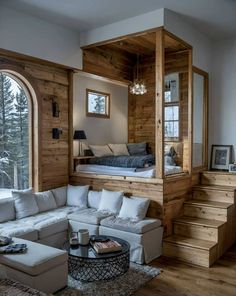 a living room filled with furniture and a large window next to a staircase leading up to a bed