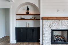 a fireplace in a living room with white walls and wood flooring on the other side