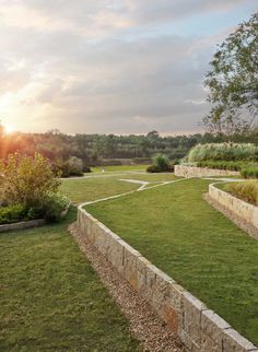 the sun is setting over an open field with stone walls and green grass in the foreground