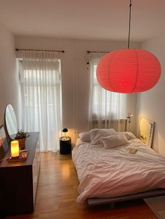 a bedroom with a bed, mirror and lamp on the wall next to it's windows