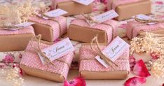 small gift boxes with tags on them sitting on a table next to flowers and petals