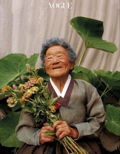 an old woman holding flowers in her hands