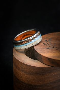 a wooden box with a ring on top of it and a black background behind it