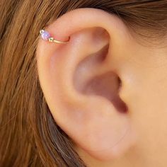 a woman's ear is shown with a small pink stone in the middle of it