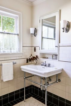 a white sink sitting under a bathroom window next to a towel dispenser