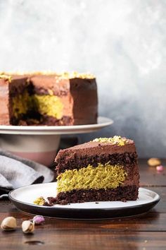 a slice of chocolate cake on a plate next to the rest of the cake, with one piece missing