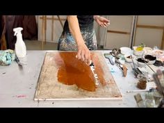 a woman is making something brown on a sheet of paper in an art studio area