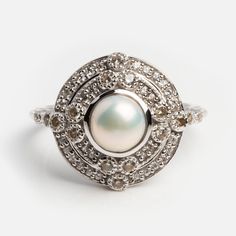 a pearl and diamond ring on a white background