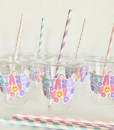 four cups with straws in them sitting on a table next to two paper straws