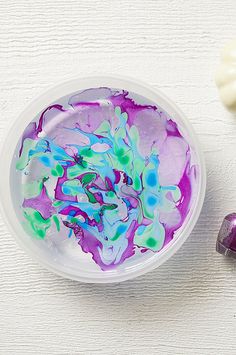 a bowl filled with purple and green liquid next to two white candy candies on top of a table