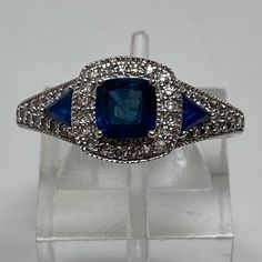 a blue and white diamond ring sitting on top of a glass stand