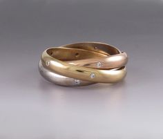 two gold and silver rings with diamonds on each one, set against a gray background