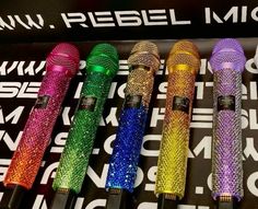 five colorful microphones sitting on top of each other in front of a black sign