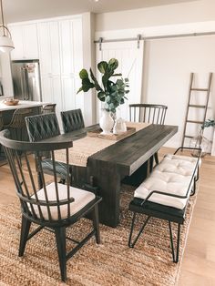 a dining room table with chairs and a bench in front of it on top of a rug