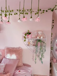 a bedroom with pink walls and flowers hanging from the ceiling, along with stuffed animals