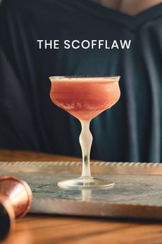 a person sitting at a table with a drink in front of them and the words, the scofflaw on it