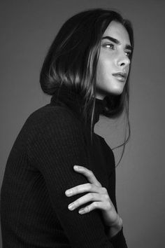 a woman with her arms crossed posing for a black and white photo, she is wearing a turtle neck sweater