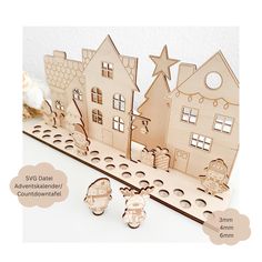 a wooden cutout of three houses with christmas decorations