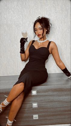 a woman sitting on top of a wooden table holding a wine glass in her hand