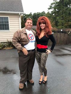 a man standing next to a woman on top of a wet ground in front of a house