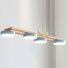 three light fixtures hanging from a wooden beam in a room with white walls and flooring