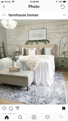 a bedroom with white bedding, pillows and rugs on the floor in front of a wooden wall