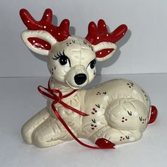 a ceramic figurine of a deer with red antlers on it's head