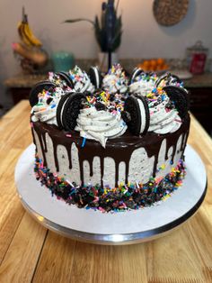 a chocolate cake with white frosting and sprinkles on a wooden table