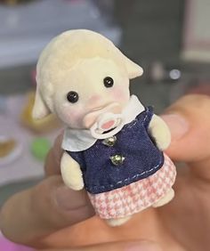 a hand holding a small stuffed animal with a dress on it's body and eyes