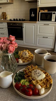 two plates with waffles, tomatoes, cucumbers and other food