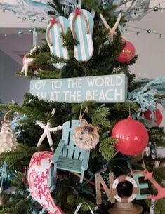 a christmas tree decorated with beach themed ornaments and decorations, including an ornament that says joy to the world i'm at the beach