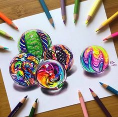 some colored pencils are laying on top of a sheet of paper with different designs