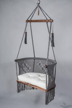 a hanging chair with white cushions and tassels