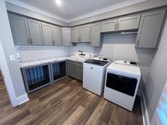 an empty kitchen with white appliances and gray cabinets