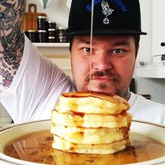 a man holding up a stack of pancakes with syrup on it