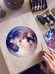 a person is painting the moon on a piece of paper with watercolors and paintbrushes