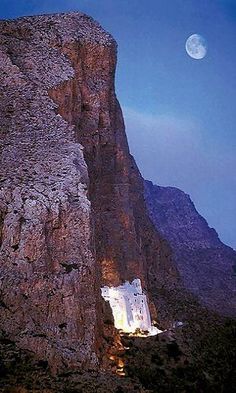 the moon shines brightly above a rocky mountain