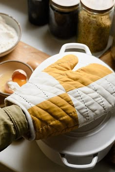 a person wearing gloves is cooking on a stove top with spices and other ingredients in the background