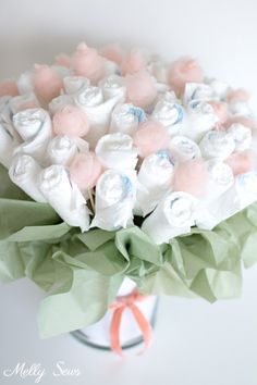 a bouquet of white and pink flowers in a glass vase with ribbon on the side