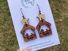 a pair of wooden earrings with an image of a baby jesus in the manger