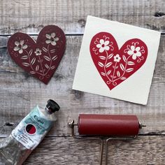 paper hearts, paint roller and glue sitting on top of a wooden table next to some crafting supplies