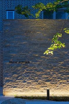 a bench sitting in front of a tall brick wall with writing written on the side