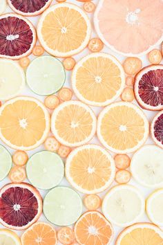 oranges, limes and grapefruit slices are arranged on a white surface