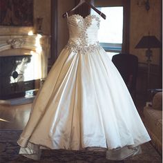 a wedding dress on display in front of a fireplace