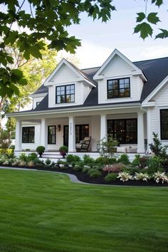 a large white house with lots of windows and plants on the front lawn in front of it