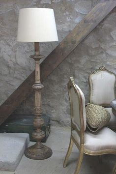 a chair and lamp sitting in front of a stone wall next to a stair case