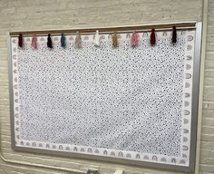 a white wall hanging on the side of a brick building with tassels attached to it